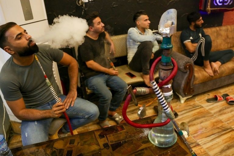 Iraqi men smoke waterpipes at a coffee shop in Iraq's holy city of Karbala, where the pipes are traditionally made of locally carved wood.