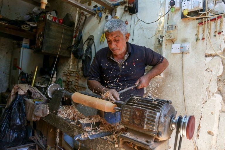 A carpenter in Karbala shaves a piece of wood to make a waterpipe at his workshop using local white willow wood.