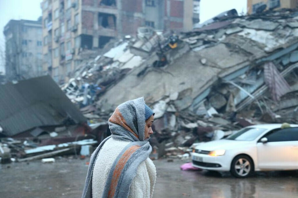 A woman stands near a collapsed building after an earthquake in Kahramanmaras, Turkiye February 6, 2023. REUTERS