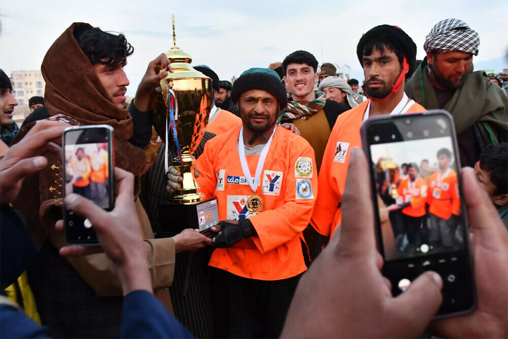 Horseman Sarwar Pahlawan (C) of the Yama Petroleum Team holds up the Buzkashi League trophy after their victory in the tournament final. Photo: AFP