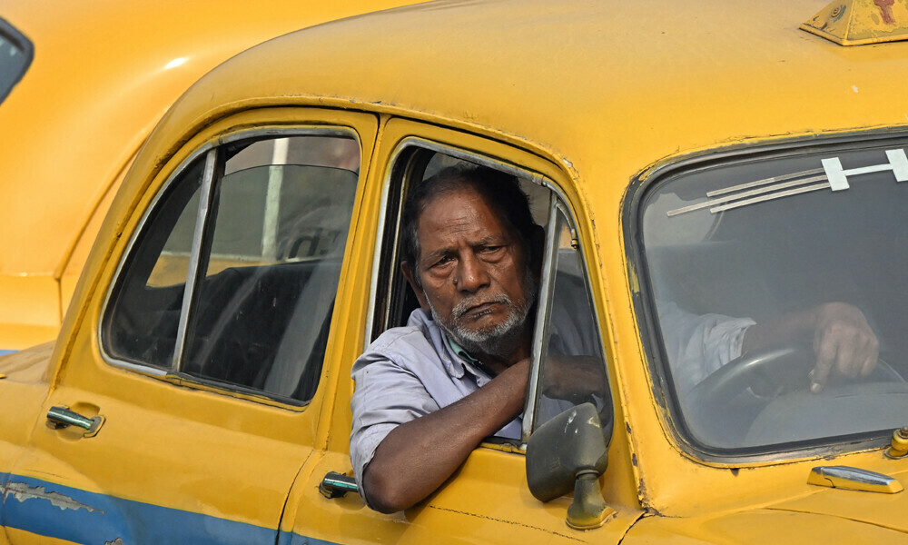 The driver of a Hindustan Ambassador yellow taxi waiting for passengers outside a railway station in Kolkata. Kolkata cherishes its past, which is why the one-time Indian capital is mourning a vanishing emblem of its faded grandeur: a hulking and noisy fleet of stately yellow taxis. Photo: AFP