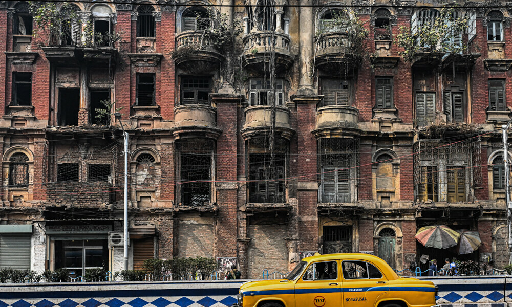The driver of a Hindustan Ambassador yellow taxi riding past a heritage building in Kolkata. Kolkata cherishes its past, which is why the one-time Indian capital is mourning a vanishing emblem of its faded grandeur: a hulking and noisy fleet of stately yellow taxis.