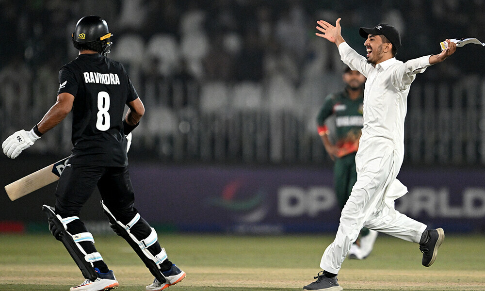 A pitch invader runs towards Rachin Ravindra (L) during the ICC Champions Trophy one-day international (ODI) cricket match between Bangladesh and New Zealand at the Rawalpindi Cricket Stadium in Rawalpindi on February 24, 2025. Photo: AFP