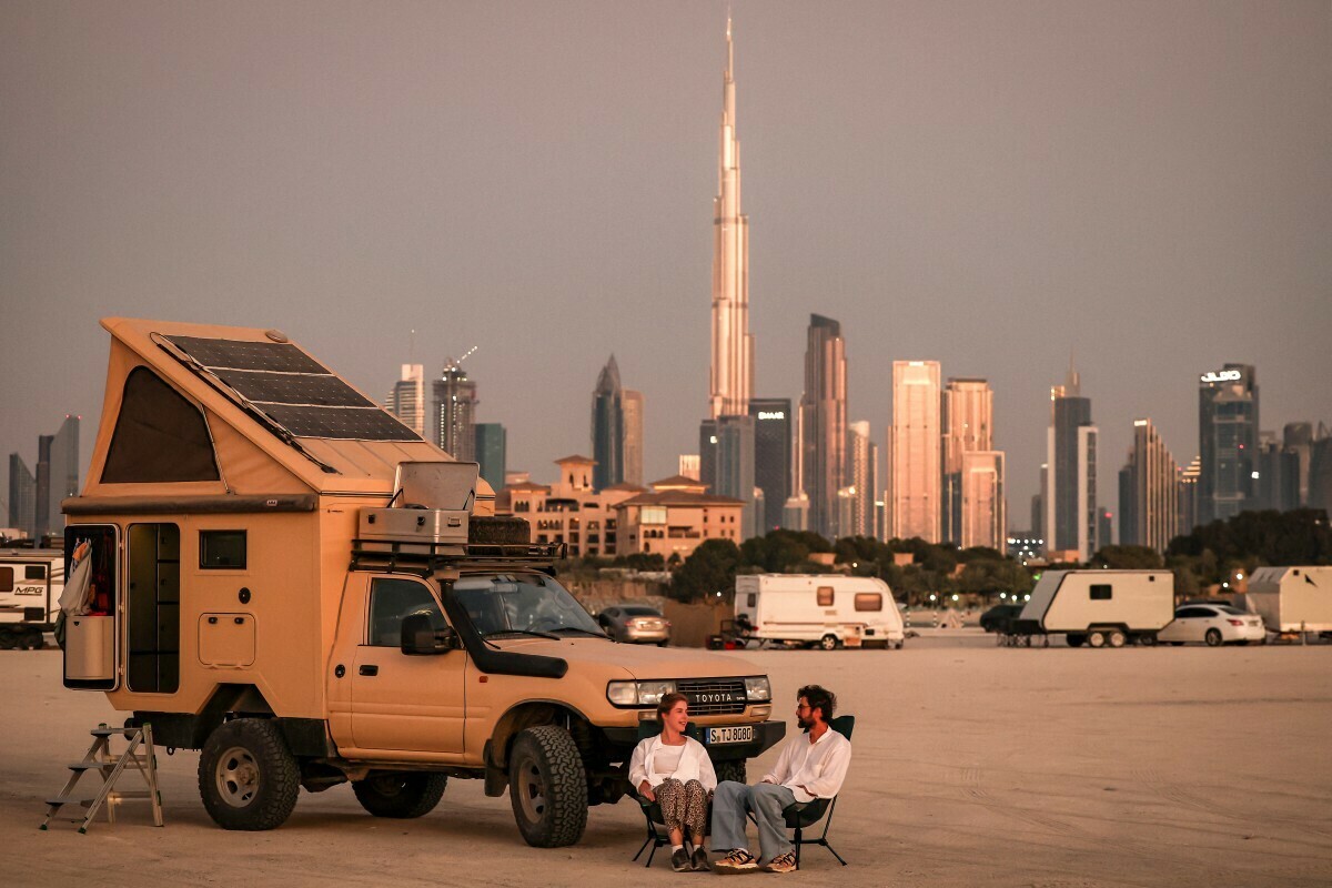  A couple sits outside a camper vehicle parked by a backdrop of the Dubai skyline including Burj Khalifah, the world&rsquo;s tallest structure, on February 4, 2025. Photo: AFP 