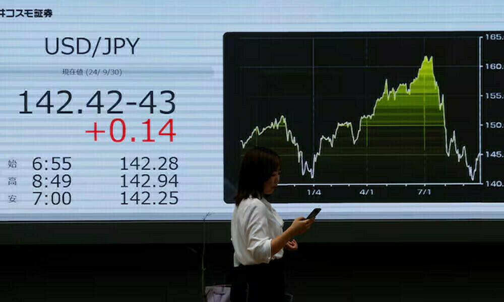 A passer by walks past an electronic screen displaying the current Japanese Yen exchange rate against the U.S. dollar outside a brokerage in Tokyo, Japan. Photo: Reuters