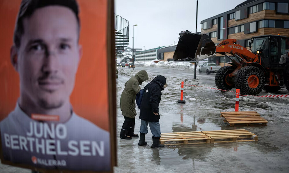 People cross a street past an election campaign poster ahead of a March 11 general election in Nuuk, Greenland. Photo: Reuters