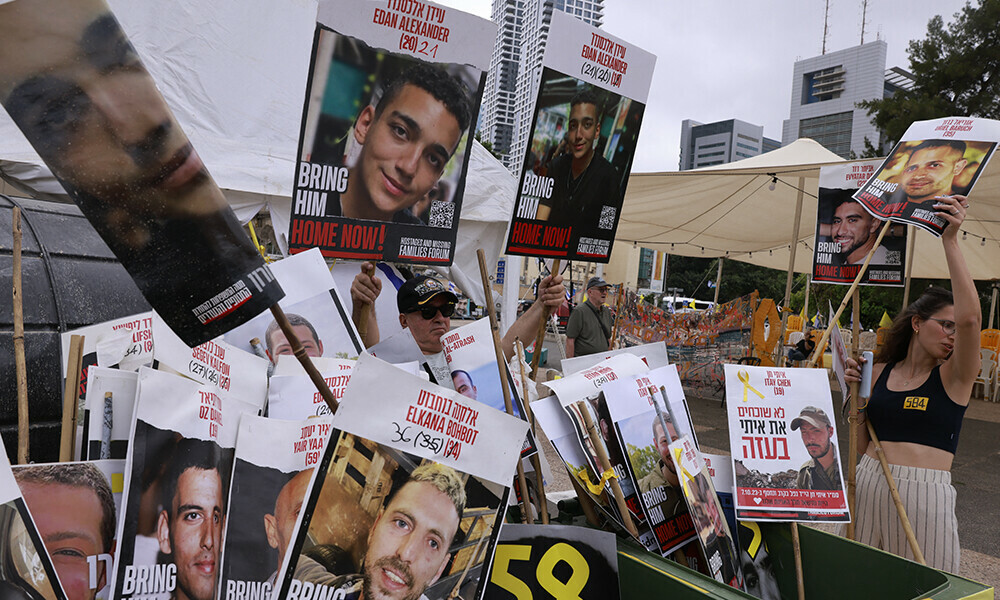 A woman holds a poster bearing a portrait of an Israeli hostage held by Hamas in Gaza since October 2023 next to several portaits, including two (C) of Israeli-US captive Edan Alexander, at Hostages Square in Tel Aviv as people wait for his release on May 12, 2025. Photo: AFP