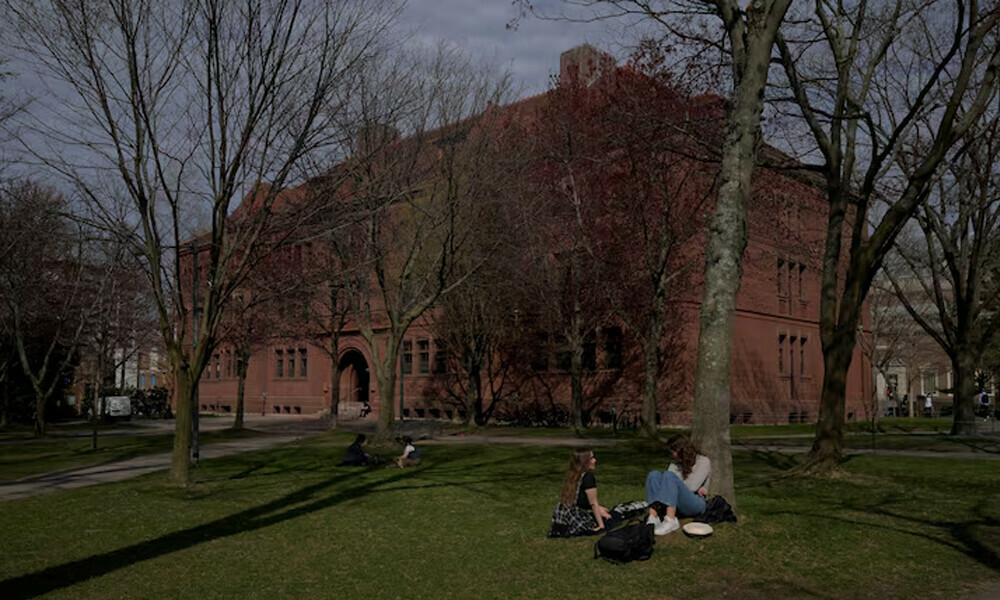 People sit on the grass at the campus of Harvard University in Cambridge, Massachusetts, U.S., April 15, 2025. REUTERS