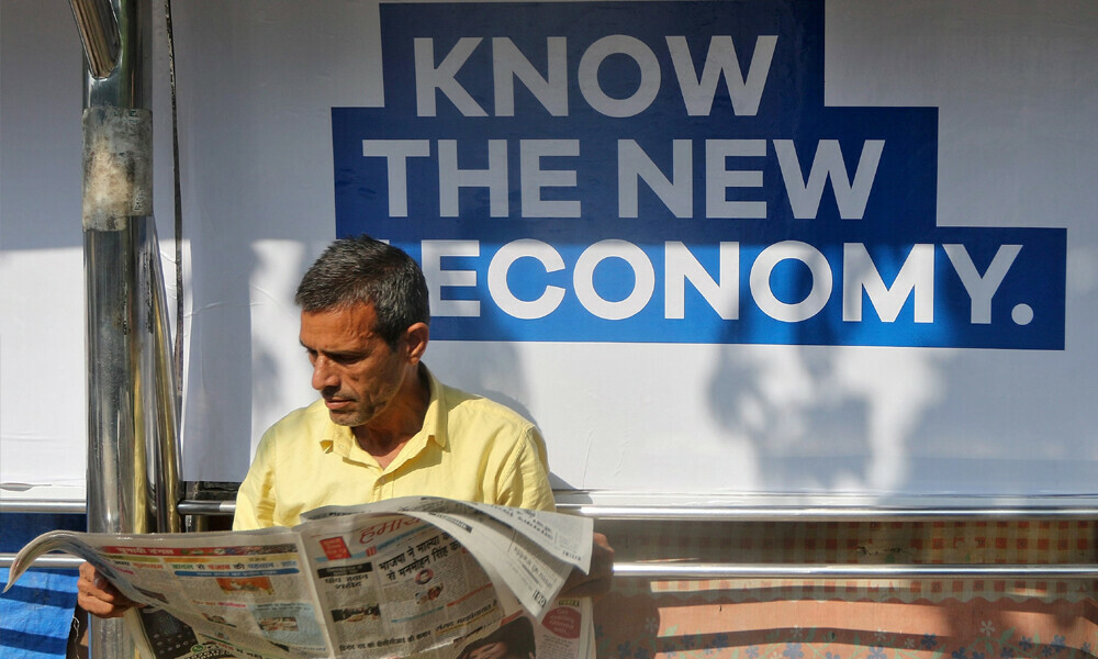 A man reads a newspaper as he waits for public transport at a bus stop in Mumbai, India, Photo: Reuters
