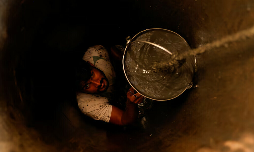 A man cleans out a small well in Chandrapur, India. Photo: Reuters