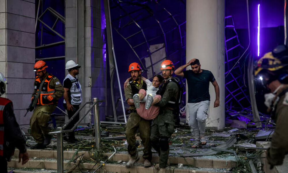 Rescuers evacuate an injured woman from an impacted residential building following a missile attack from Iran on Israel, central Israel, June 16, 2025. Photo: Reuters