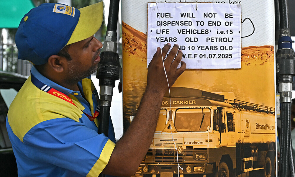 A fuel attendant displays a notice announcing the ban on refuelling petrol cars older than 15 years and diesel vehicles older than 10 years, displayed at a gas station in New Delhi on July 1, 2025. Photo: AFP
