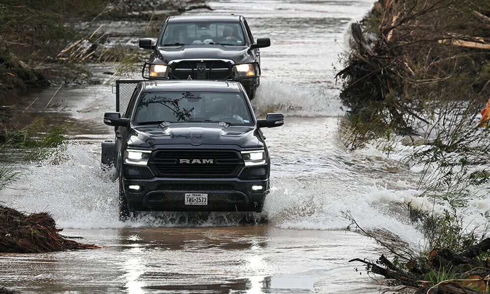 Trucks drive through a flooded and damaged road in Hunt, Texas, on July 6, 2025, following severe flash flooding that occured during the July 4 holiday weekend. Photo: AFP