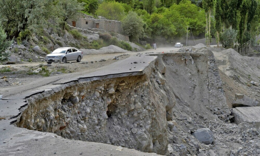 A vehicle drives past a partially collapsed section of the Karakoram Highway damaged after a lake outburst near Hassanabad village of Gilgit-Baltistan region on June 9, 2022. Photo: AFP/File