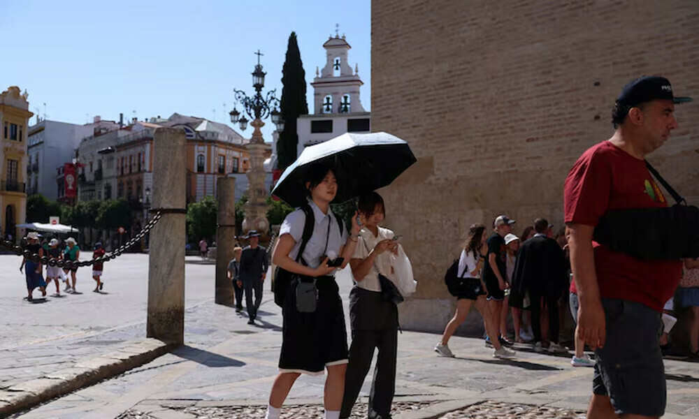 People walk during a heatwave, in Seville, Spain, July 2, 2025. REUTERS