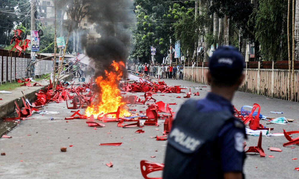 An anti-riot police personnel stands guard along a street ravaged with burning plastic chairs, allegedly vandalised by the Awami League party activists rebuking a rally by the newly formed Jatiya Nagarik Party, or National Citizen&rsquo;s Party in Gopalganj on July 16, 2025. Photo: AFP