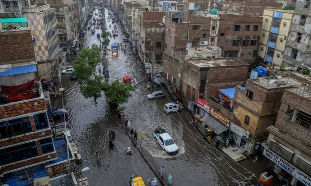 Commuters make their way through a flooded street during heavy monsoon rains in Hyderabad on July 14, 2025. Photo: AFP