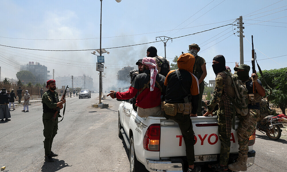 Smoke rises in the distance as Beduin and tribal fighters gather in the city of Sweida in southern Syria&rsquo;s Druze majority province on July 19, 2025. Photo: AFP