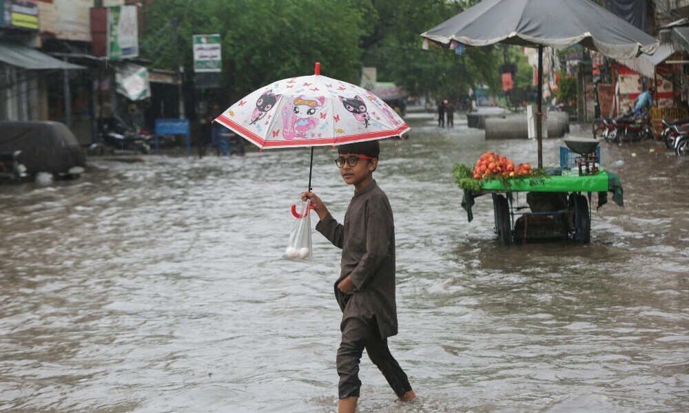 A child holds an umbrella as he wades through a flooded street after a downpour in Lahore on July 9, 2025. Photo: Reuters