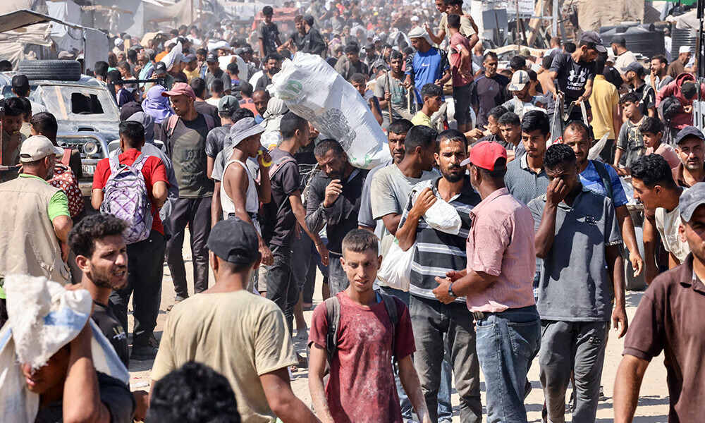 People carry food parcels and bags in the al-Mawasi camp in Rafah in the southern Gaza Strip, that were picked up from the Rafah corridor on July 27, 2025. Photo: AFP