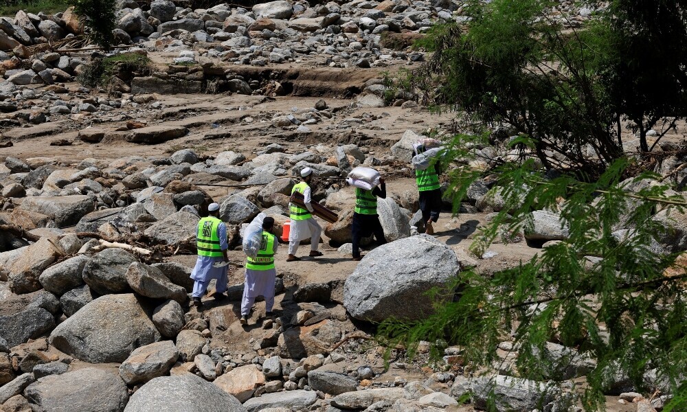 Volunteers carry relief handouts to deliver them to affected people, following a storm that caused heavy rains and flooding in the Qadir Nagar area of Buner district of Khyber Pakhtunkhwa on August 21, 2025. Photo: Reuters