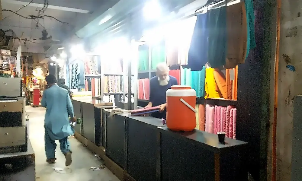 A fabric shopkeeper arranges cloth rolls at his shop in Karimabad market. Photo: Business Recorder