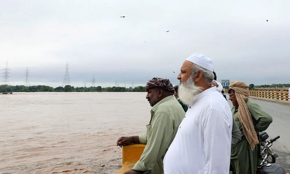  Men stand on a bridge over the Chenab River, following the monsoon rains and rising water level in Wazirabad, in Punjab province, Pakistan August 27, 2025. REUTERS/Akhtar Soomro 