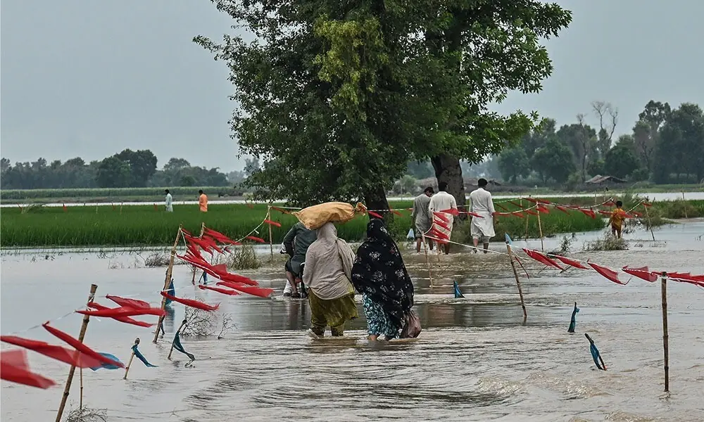  Villagers wade through floodwaters after heavy rainfall in the Kasur district of Pakistan&rsquo;s Punjab province on August 24, 2025. (Photo by Arif ALI / AFP) 