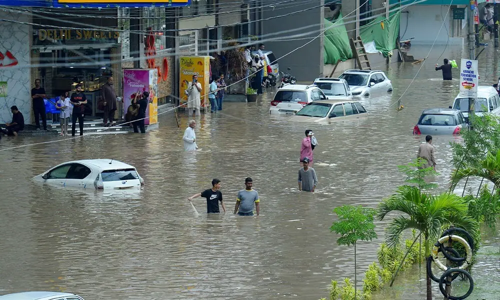  People wade through a flooded road with partially submerged vehicles after the monsoon rain, in Karachi, Pakistan, August 19, 2025. REUTERS/Imran Ali 
