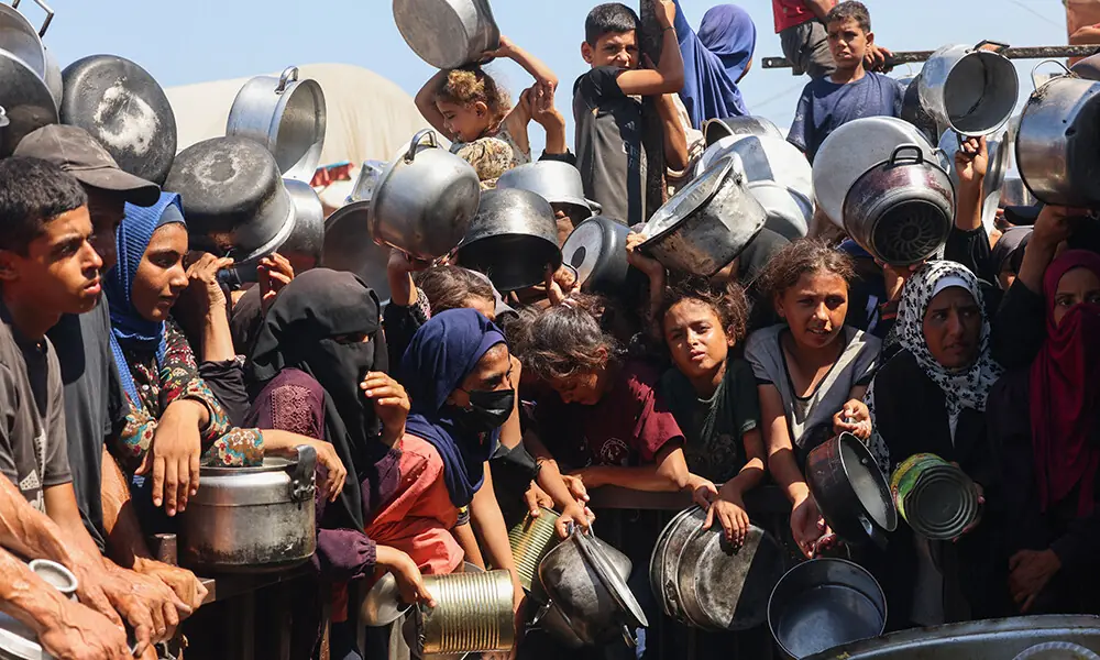 Palestinian women and children wait to receive food portions from a charity kitchen in Khan Yunis in the southern Gaza Strip on August 27, 2025. Photo: AFP