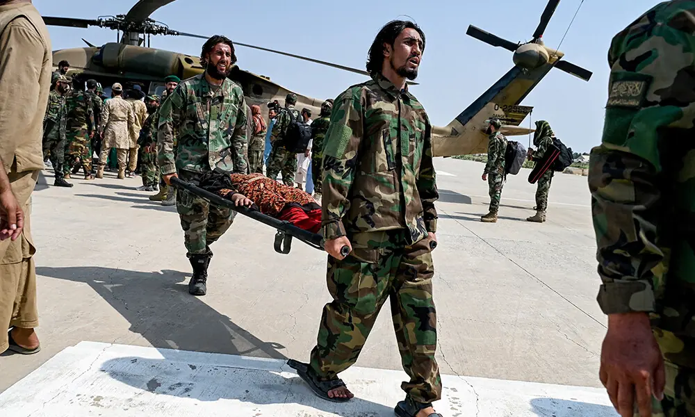 Taliban security personnel carry an earthquake victim evacuated by a military helicopter from the Nurgal district of Kunar province, after her arrival for medical assistance in Jalalabad on September 1, 2025. Photo: AFP