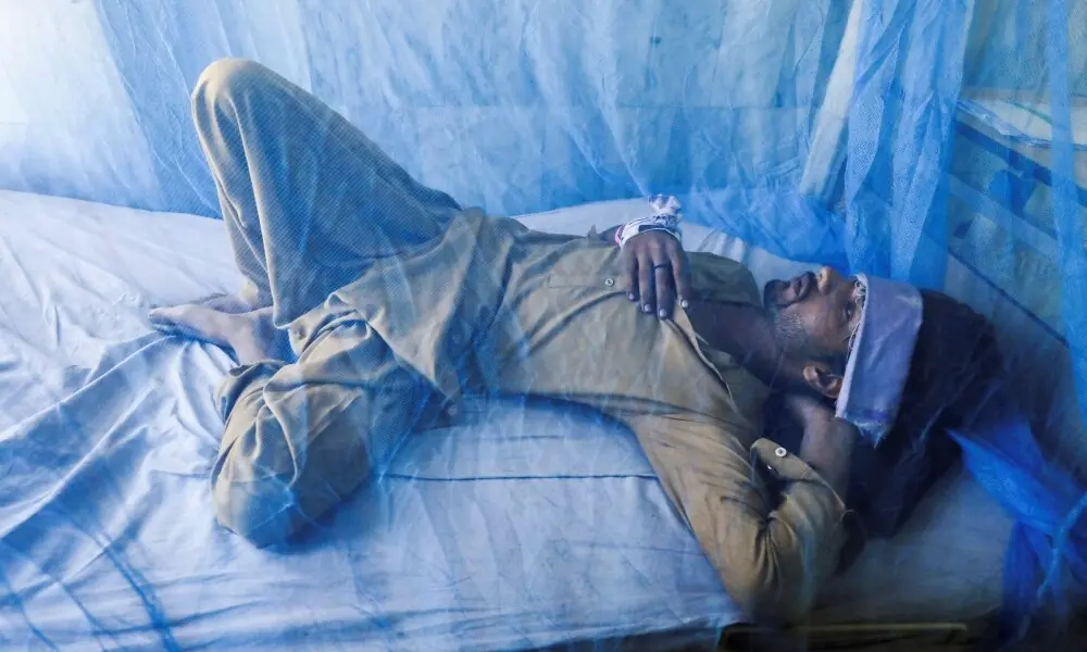 A patient, suffering from dengue fever, lies under a mosquito net inside a dengue ward at Lady Reading Hospital in Peshawar. Photo: Reuters/File