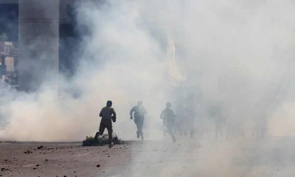 Police officers and supporters of Tehreek-e-Labbaik Pakistan (TLP) run amid tear gas fired by police during a solidarity march for Gaza in Lahore on October 10, 2025. Photo: Reuters