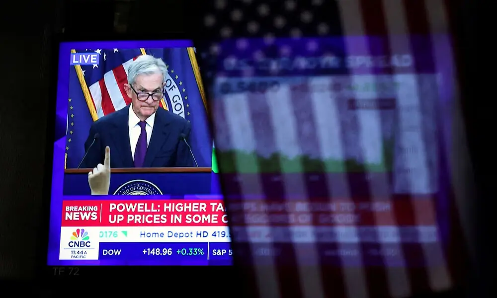 A U.S. flag hangs in front of a screen that broadcasts a news conference by U.S. Federal Reserve Chair Jerome Powell following the Fed rate announcement, on the floor of the New York Stock Exchange (NYSE) in New York City, U.S., September 17, 2025. REUTERS