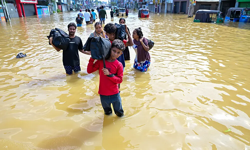 People with their belongings wade through a flooded street after heavy rainfall in Wellampitiya on the outskirts of Colombo on November 30, 2025. Photo: AFP