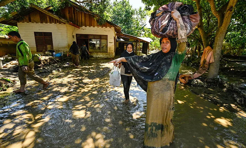 A woman carries belongings in a flooded area in Meureudu, Pidie Jaya district in Indonesia&rsquo;s Aceh province on November 30, 2025. Photo: AFP