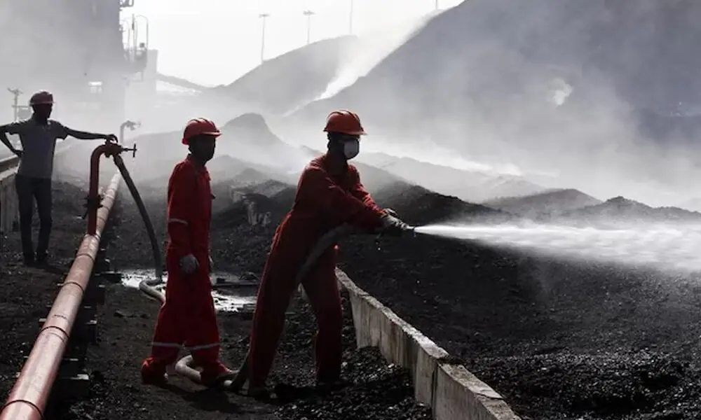 A worker sprays water over piles of coal at Mundra Port Coal Terminal in the western Indian state of Gujarat April 2, 2014. File Photo: Reuters