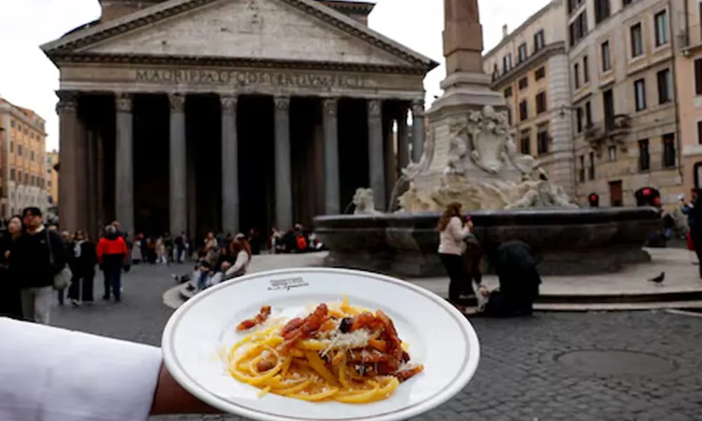 A waiter shows a plate of traditional pasta Carbonara in front of the Pantheon in Rome, Italy, December 3, 2025. REUTERS