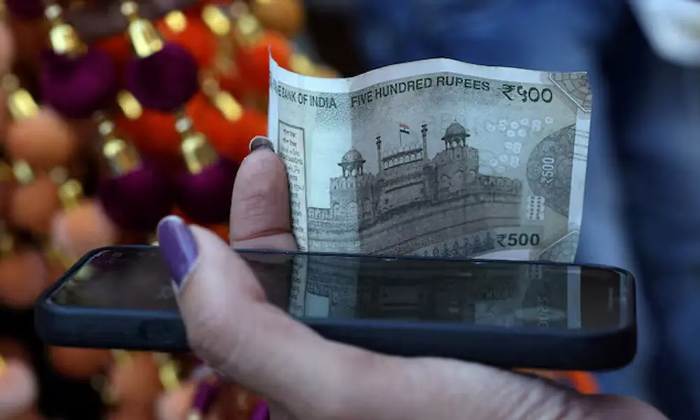 A woman holds a five-hundred-rupee currency note in the old quarters of Delhi, India, September 25, 2025. REUTERS