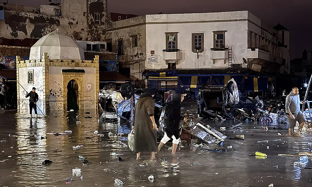 People wade through a square after a flash flood in Safi on December 14, 2025. Photo: AFP