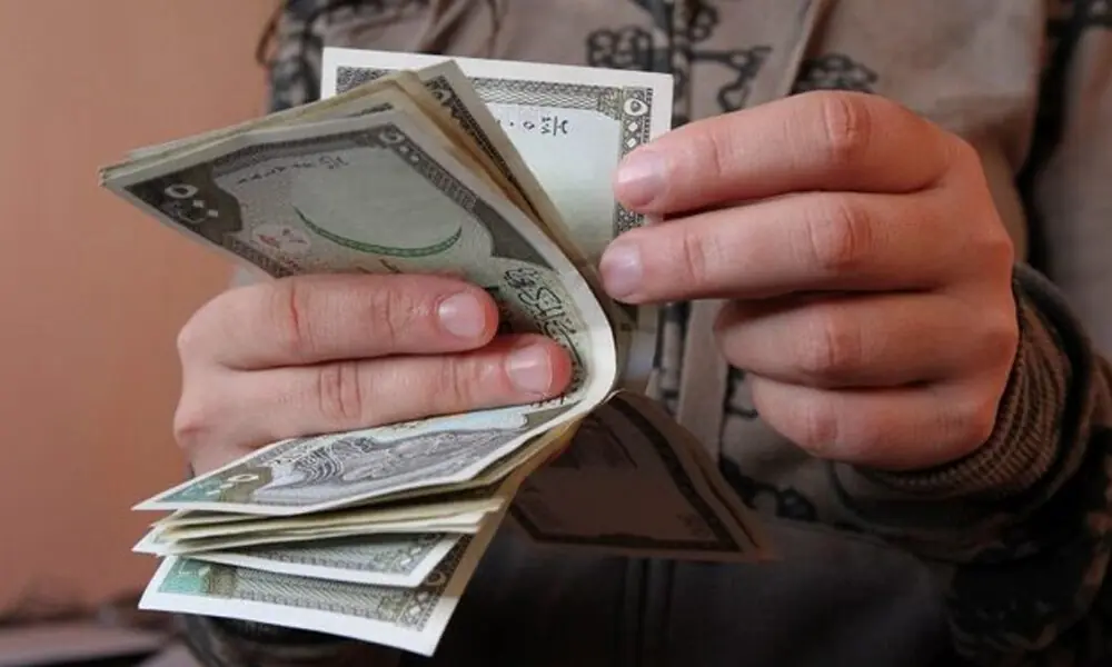 A man counts Syrian currency notes in Damascus November 13, 2012. File Photo: Reuters