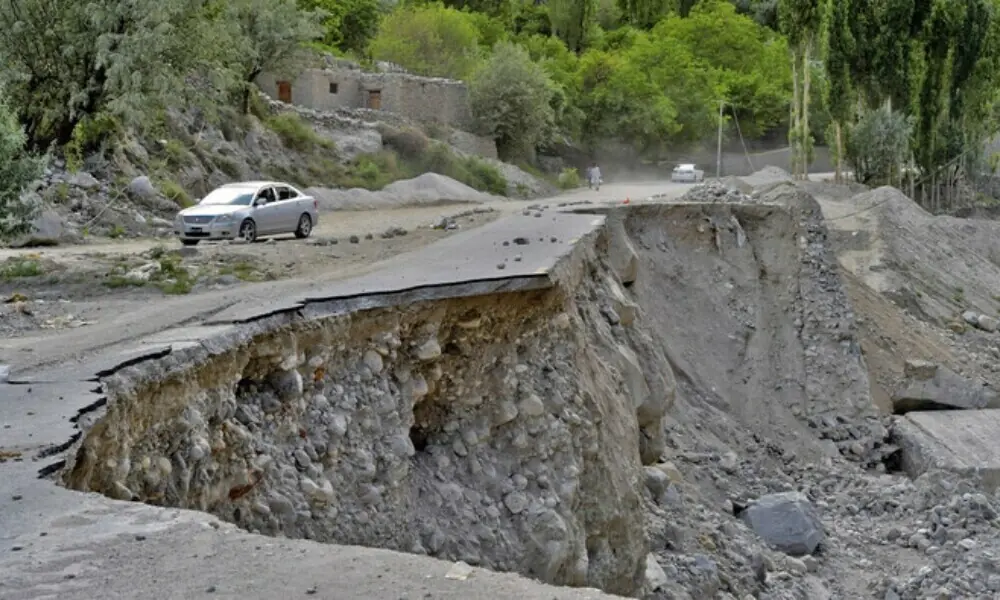 A vehicle drives past a partially collapsed section of the Karakoram Highway damaged after a lake outburst near Hassanabad village of Gilgit-Baltistan region on June 9, 2022. Photo: AFP/File