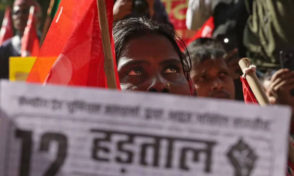 A demonstrator holds a flag during a day-long strike against what they say are anti-labour policies and the India-U.S. trade framework, at Jantar Mantar in New Delhi, India, February 12, 2026. REUTERS