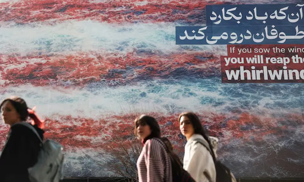 Iranian women walk past an anti-U.S. billboard in Tehran, Iran, February 19, 2026. Photo: Reuters