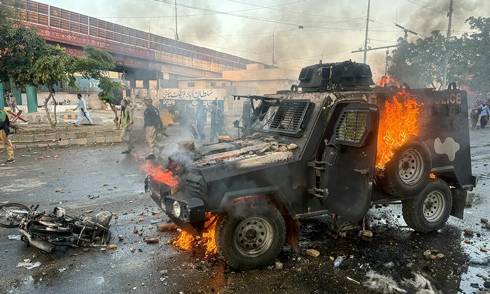 Policemen walk past a burning armoured vehicle set on fire by protestors outside the US consulate in Karachi on March 1, 2026. Photo: AFP
