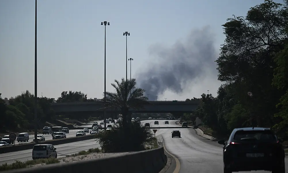 Motorists drive along a street as smoke rises from a reported Iranian strike in the area where the US Embassy is located in Kuwait City on March 2, 2026. Photo: AFP