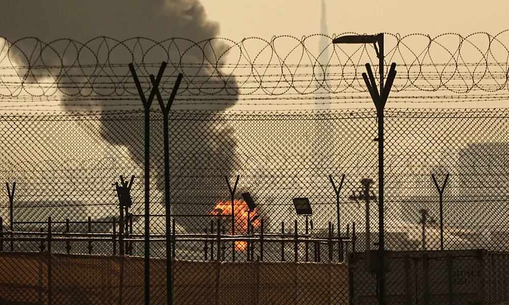 The Dubai skyline with the landmark Burj Khalifa skyscraper (R) is pictured as a smoke plume rises from an ongoing fire near Dubai International Airport on March 16, 2026. Photo: AFP