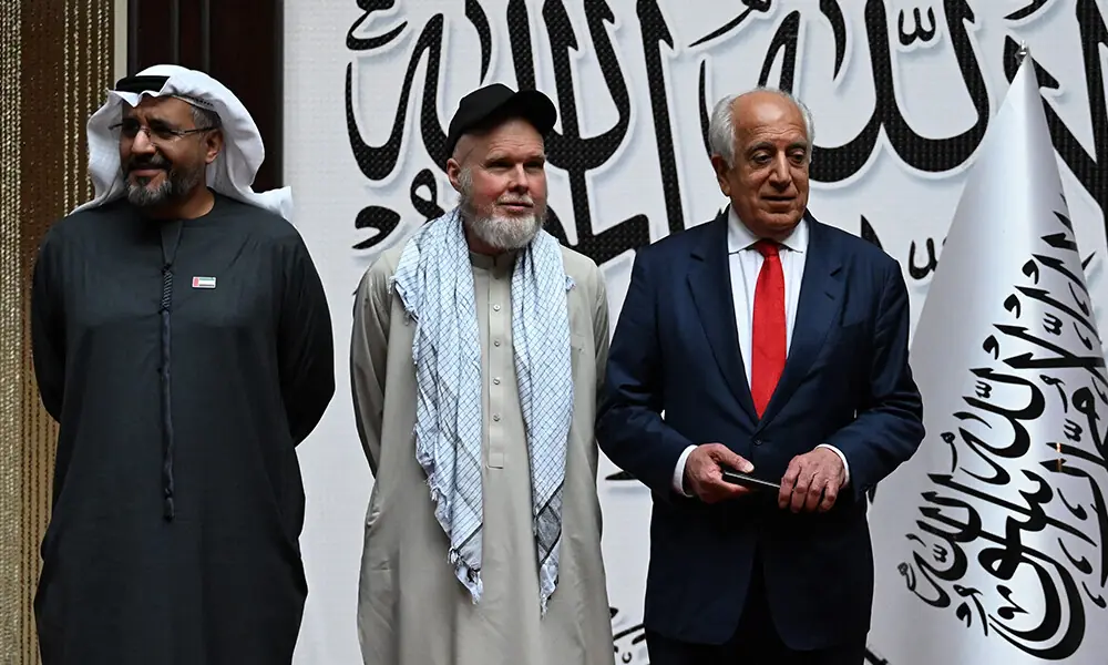 US citizen Dennis Coyle (C) upon his release by the Taliban, poses with US former special envoy to Afghanistan Zalmay Khalilzad (R) and the UAE ambassador to Kabul Saif Mohammed Al-Ketbi (L) at the airport in Kabul on March 24, 2026. Photo: AFP