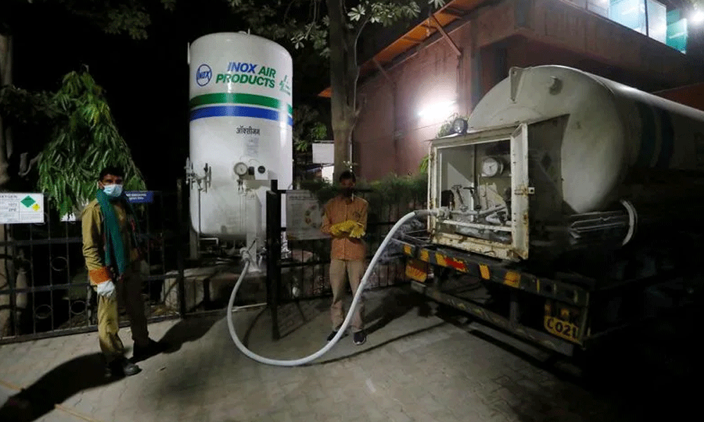 FILE PHOTO: Workers stand as a tank is filled with liquid oxygen at a hospital, in New Delhi. REUTERS
