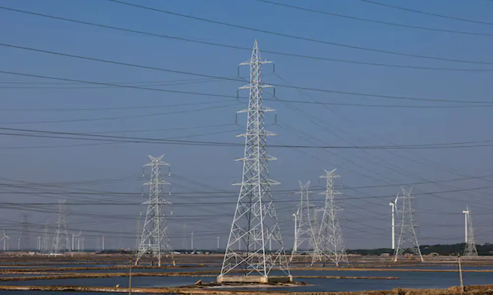 A view shows high-tension electricity power line pylons and power generating windmill turbines on Ahmedabad-Bhuj national highway near Surajbari village in the western state of Gujarat, India, November 28, 2024. File Photo: Reuters A view shows high-tension electricity power line pylons and power generating windmill turbines on Ahmedabad-Bhuj national highway near Surajbari village in the western state of Gujarat, India, November 28, 2024. File Photo: Reuters